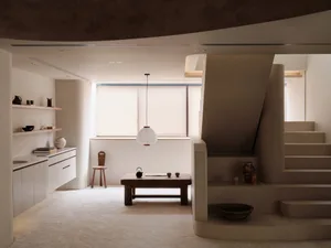 Open living area with white walls, flooring, and modern furniture, featuring two staircases and ample seating and storage options