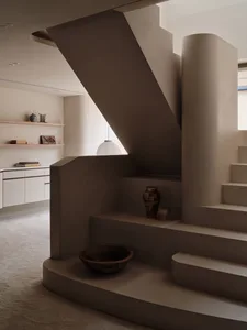 A house interior with two sets of concrete stairs, one on each side, and a decorative bowl near the bottom stairs
