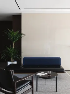 Cozy modern living space with a stone wall, a couch, chair, and dining table, featuring potted plants and a vase