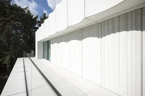 A modern building with a curved wall and a large glass window, featuring a minimalist and elegant design