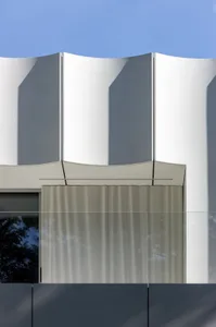 A modern building with a curved design and glass facade, featuring a bright and airy interior with natural light