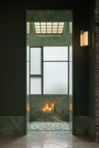 Bathroom with a green tiled wall, a shower area, and lit candles creating a warm and relaxing atmosphere