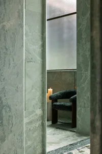 Bathroom with a shower stall containing a wooden chair with a black seat and two candles on the floor for a cozy ambiance