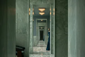 A dimly lit hallway with marble walls, lined with multiple doors on both sides, creating a mysterious atmosphere