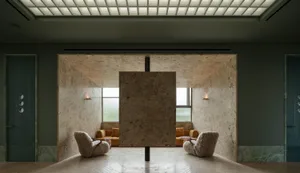 Modern living space with a large stone wall, two chairs, and a couch, featuring a minimalist and warm atmosphere