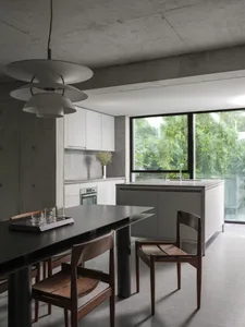 A cozy kitchen dining space with a wooden table and chairs, surrounded by a potted plant and various tableware
