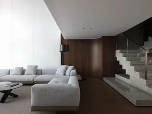 Open living area with a large couch, a chair, and a carpeted floor, featuring a warm and inviting atmosphere with wooden accents and good lighting