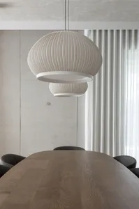 A modern dining space with a wooden table surrounded by chairs, lit by hanging lamps and providing a comfortable seating arrangement