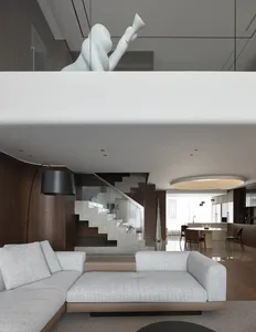 Open living area with a couch, dining table, chairs, and a statue above the staircase, featuring white walls and wooden floors in a bright and inviting atmosphere