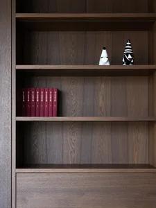 A wooden bookshelf filled with books in a cozy living area, creating a warm and inviting atmosphere for reading or studying