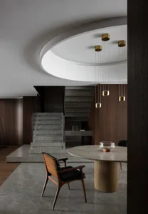 Cozy living space with a dining table surrounded by chairs, a bowl on the table, and a staircase adding depth