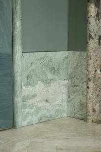 A modern bathroom with a marble wall and green marble countertop, featuring a sophisticated and elegant design with warm lighting