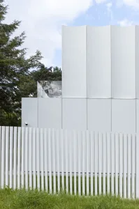 A modern building with a concrete exterior, surrounded by trees and greenery, creating a serene environment