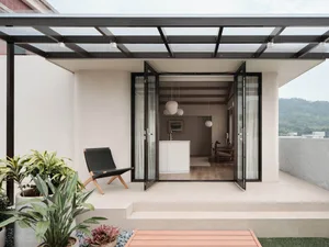 Open concept living area with a large window, kitchen, dining table, and comfortable seating, featuring natural light, decorative elements, and a sense of comfort and functionality