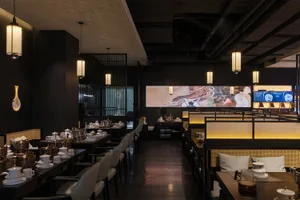 Modern restaurant interior with dining area, TVs on walls, and comfortable seating