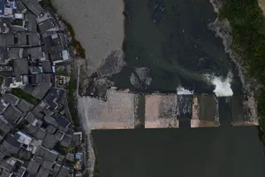 A cityscape with a dam constructed from concrete, surrounded by buildings and a body of water