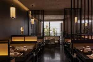 Modern restaurant interior with tables, chairs, bar, and potted plants, featuring a stylish and inviting atmosphere