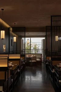 Modern restaurant interior with wooden paneling, potted plants, and a dining area with tables and chairs