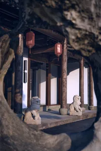 A serene Asian-style building with a white exterior, lion statues, and potted plants in a symmetrical arrangement