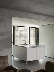 Modern kitchen with white cabinets and countertops, two sinks, and a refrigerator, giving off a clean and minimalist appearance