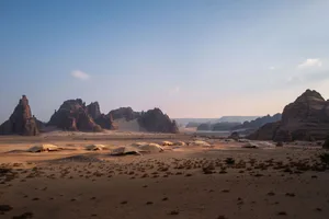 A desert landscape with mountains in the background, featuring several tents of varying sizes and positions, creating a sense of depth and adventure