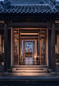 Asian-style interior with wooden walls and floors, featuring a large open area with a doorway, chairs, and a vase, creating a calm and inviting atmosphere