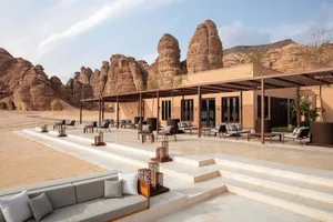 A relaxing outdoor patio area with stone walls, a wooden roof, and comfortable seating arrangements, including chairs and couches