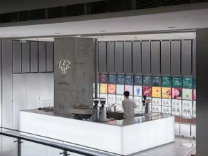 A modern coffee shop interior with a white counter and grey wall, featuring a warm and inviting atmosphere