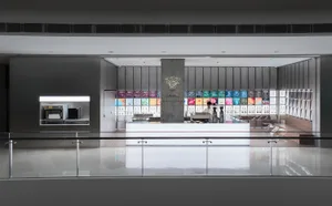 A coffee shop with a counter and a display of drinks, featuring a person standing nearby