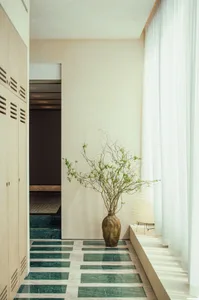 A well-decorated living space with a marble floor, a gold vase, and potted plants, with decorative bottles scattered around