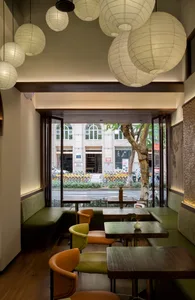 Modern restaurant interior with wood paneling, tables, chairs, and potted plants, creating a warm and inviting atmosphere
