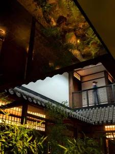 A traditional Asian building with a staircase leading to a balcony, featuring a person walking up the stairs and another person standing nearby