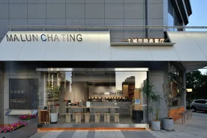 A modern Asian restaurant with grey walls, natural light, and comfortable seating areas with potted plants