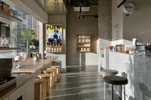 A modern restaurant interior with a large dining table surrounded by chairs, well-lit and decorated with various items