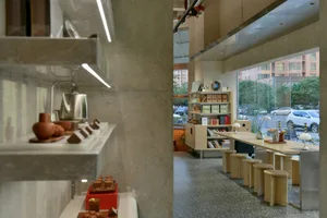 Open restaurant space with natural light, stainless steel appliances, wooden cabinets, and a dining table with chairs and decorative elements