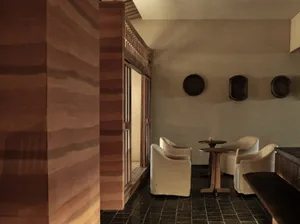 A cozy restaurant dining area with wooden chairs, a table, and a vase, creating an inviting atmosphere for a relaxed meal