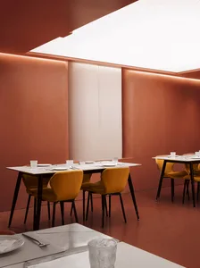 Dimly lit restaurant with red walls, multiple dining tables, and chairs, creating a cozy atmosphere