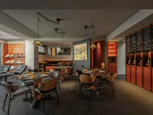 A modern restaurant with a large dining area featuring tables, chairs, and wine glasses, creating an inviting atmosphere