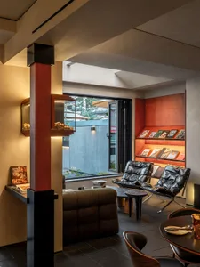 Modern living room with a couch, chairs, and dining table, surrounded by books and giving off a clean and modern vibe