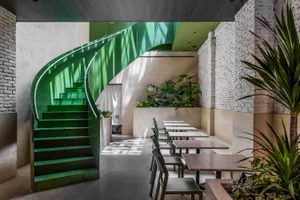 Elegant dining area with a spiral staircase, multiple chairs, and dining tables arranged throughout the space