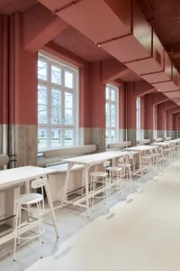 A modern dining space with pink walls, multiple tables, chairs, and benches, featuring a contemporary design with clean lines and minimalistic decoration