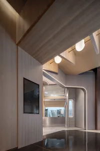 Industrial-style restaurant interior with a staircase leading to a kitchen area featuring two refrigerators and a sink