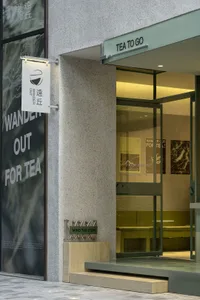 Inviting cafe with white walls, gray stone elements, and glass doors, featuring a sign that says Wander Out For Tea