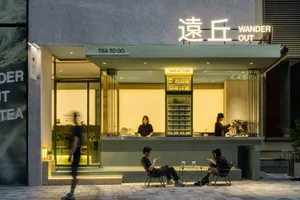 A cozy Asian restaurant with a green wall, outdoor seating, and patrons enjoying their meal