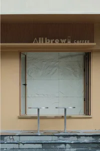 A modern coffee shop interior with metal tables, white tile walls, and a doorway leading to another area