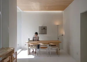 A cozy dining area with a wooden table and chairs, surrounded by white walls and a comfortable atmosphere