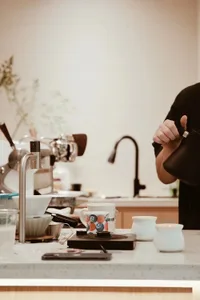 A casual kitchen with a focus on functionality, featuring a wood and metal construction, with appliances, cups, and utensils on the countertop
