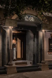 A warm and inviting restaurant entrance with a wooden doorway, stone construction, and soft lighting from two side lamps