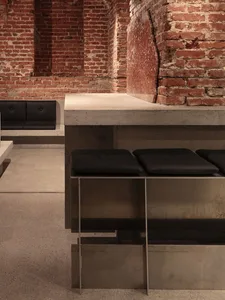 Cozy room with brick walls, two black stools, and two benches, creating a warm and inviting atmosphere