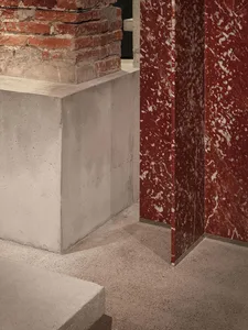A warm and inviting room with a red marble wall, stone columns, and a brick-patterned fireplace